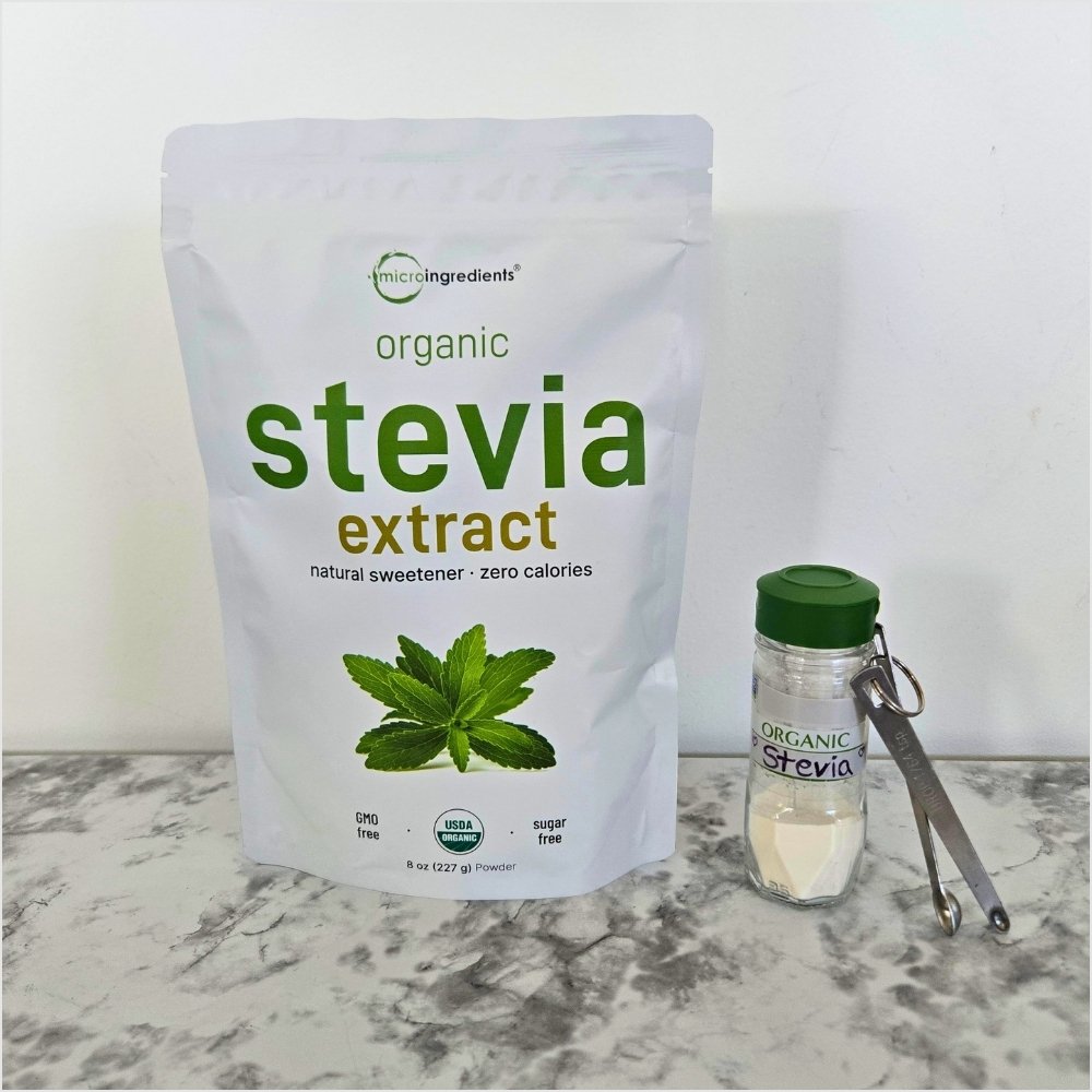 A bag of organic stevia extract beside a repurposed glass spice jar labeled Organic Stevia and a set of tiny measuring spoons